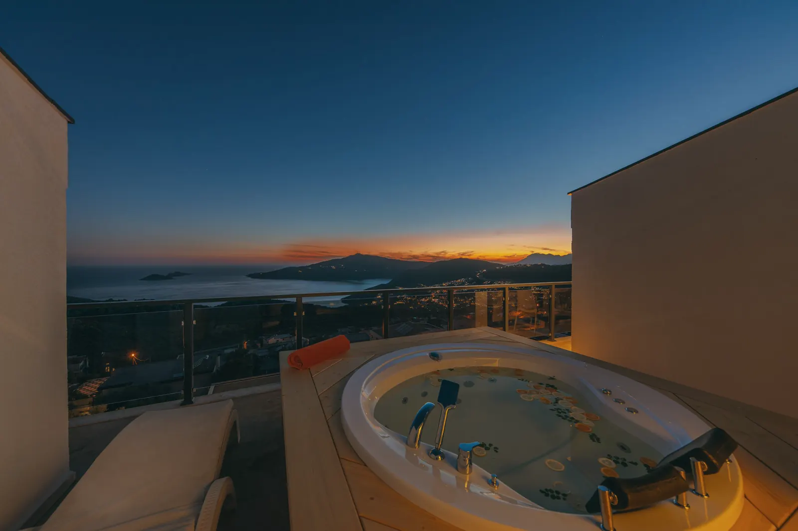 Terraza superior con jacuzzi frente a la bahía al anochecer.