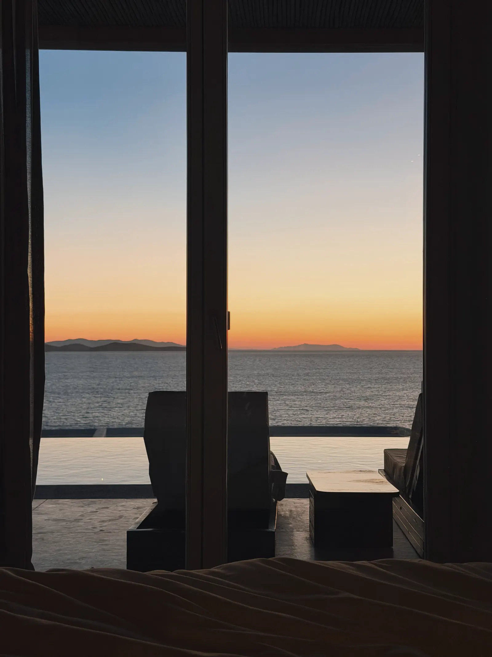 Puerta acristalada abierta al Mediterráneo al atardecer.